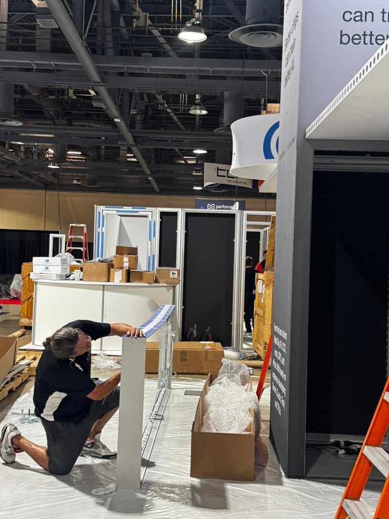 Welder fabricating metal components for trade show exhibits in a workshop setting, showcasing custom design and fabrication capabilities.